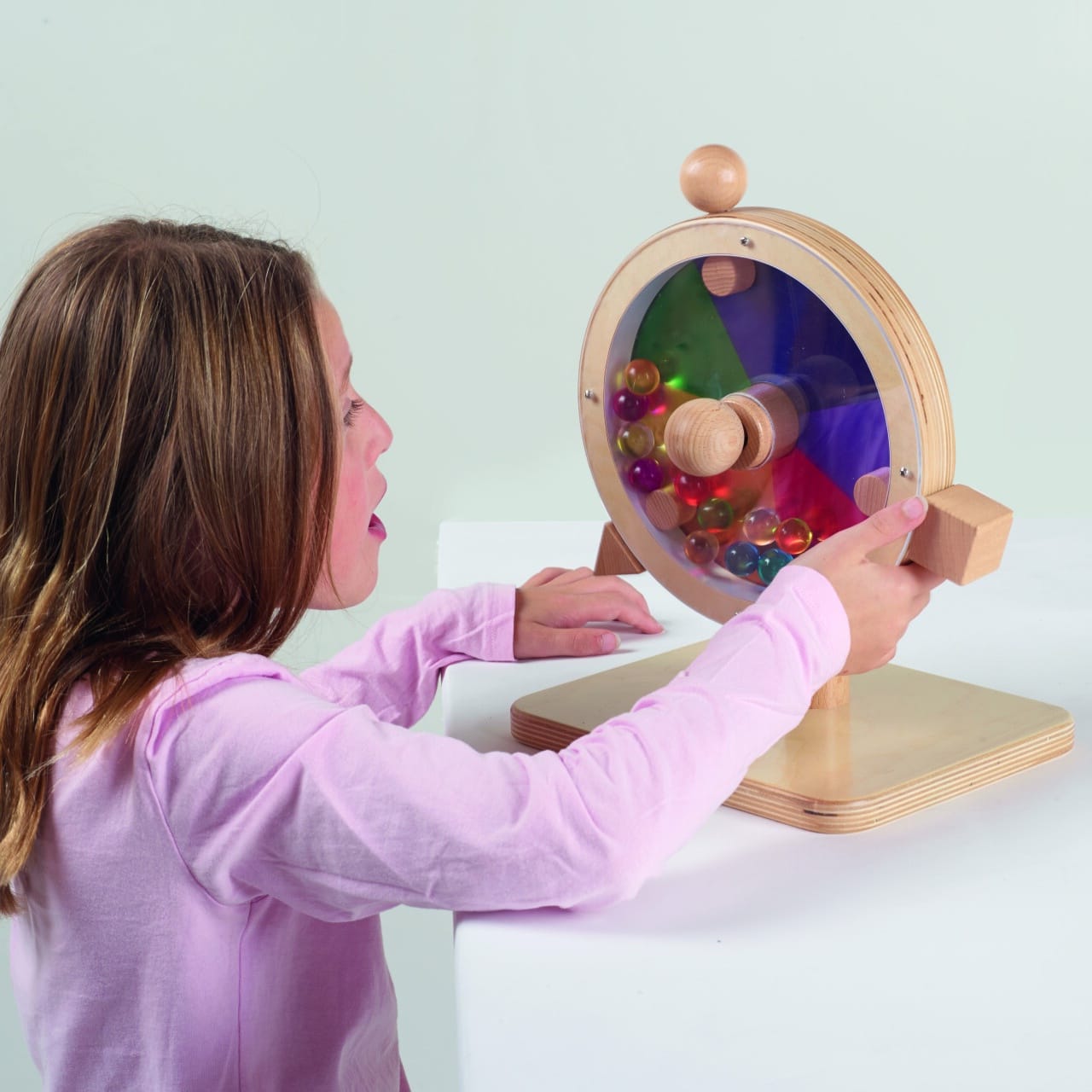 A girl playing with a wooden spectrum tumbler toy